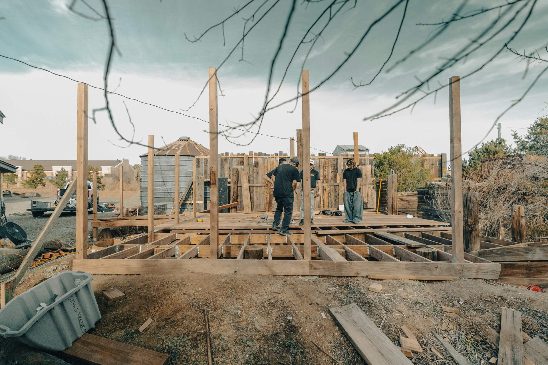 Chantier en cours : ossature et plancher en construction, intervenants sur place