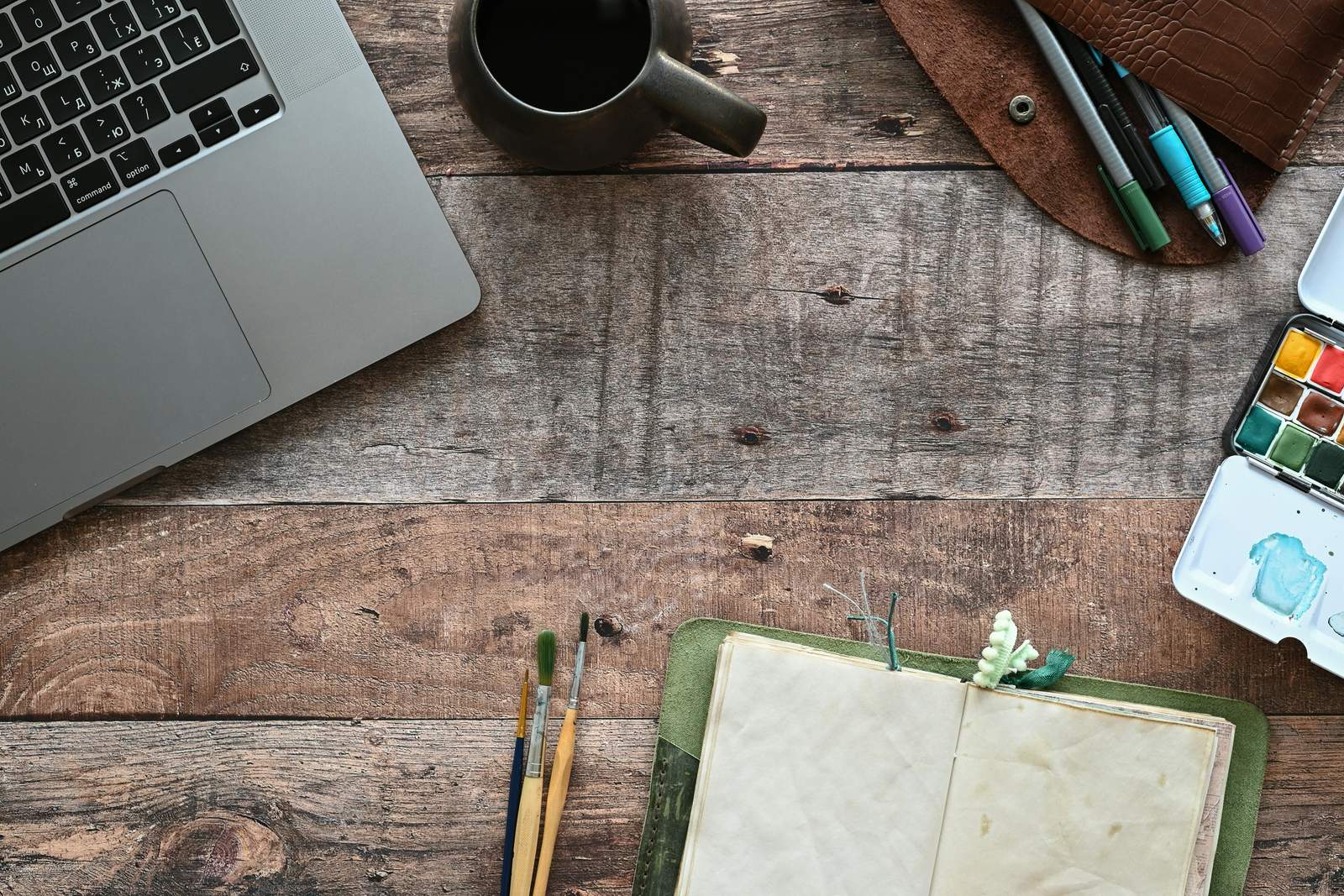 Carnet ouvert avec un stylo et une tasse de café sur un bureau en bois clair, évoquant la préparation sereine d’un projet
