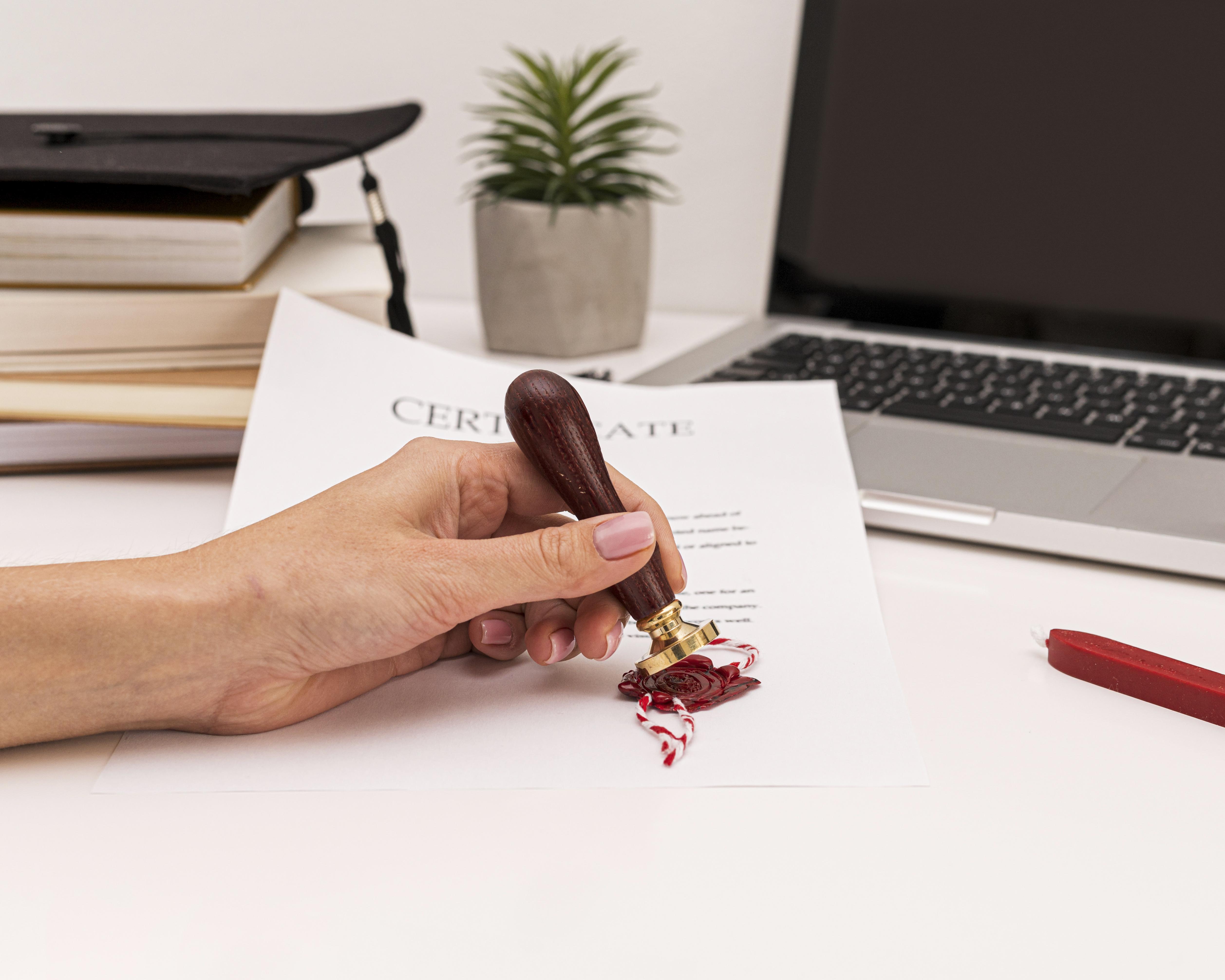 Mains qui tamponnent un acte officiel sur un bureau de notaire, dossier juridique à côté