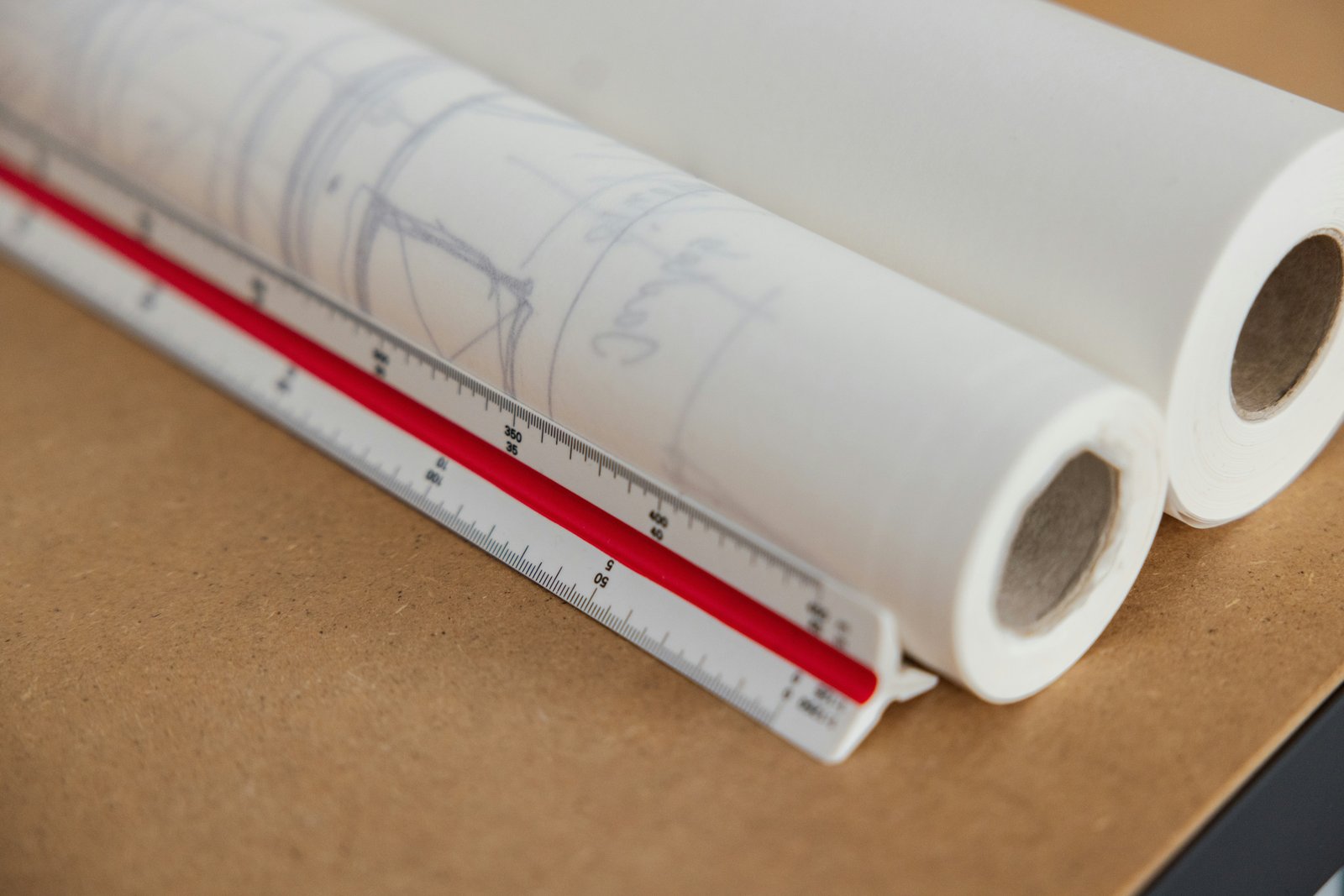 Plan d’architecte étalé sur une table avec règle, équerre et calculette